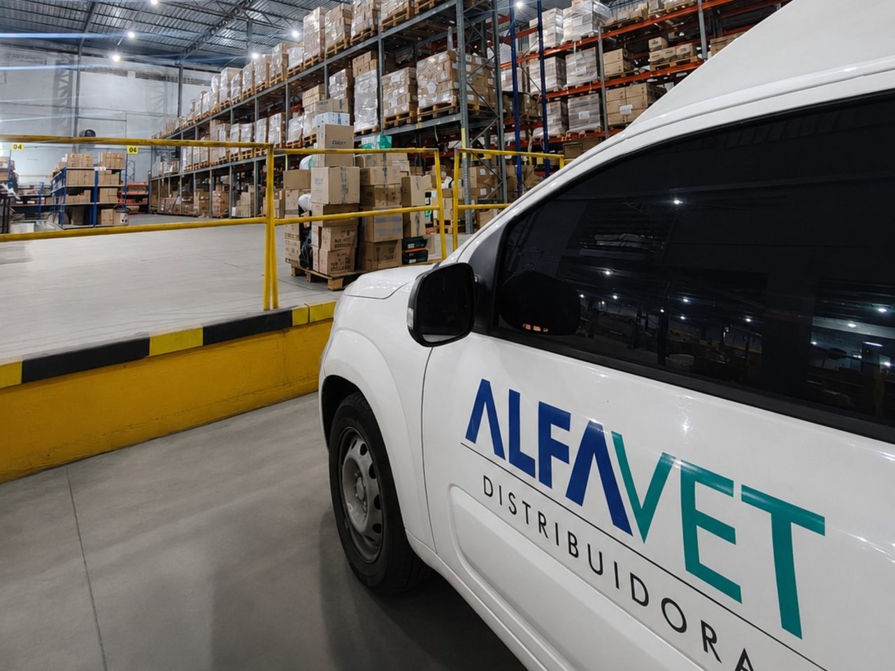 Veículo da frota na doca do centro de distribuição, com o porta-pallet abastecido ao fundo